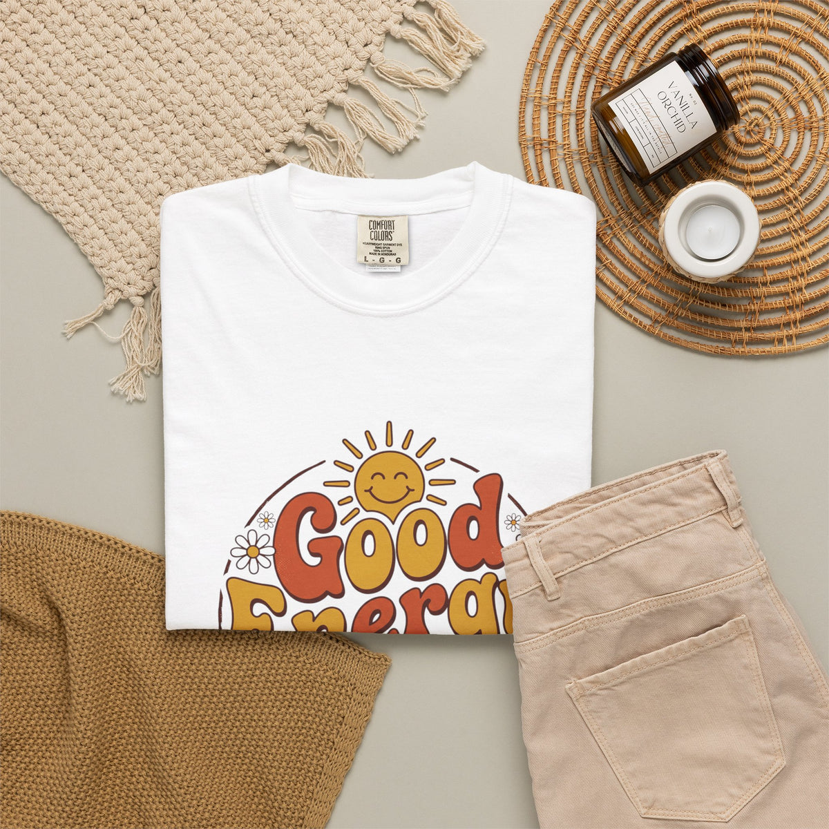 Good Energy Only T-shirt, white, styled flat lay with denim pants and a woven blanket.
