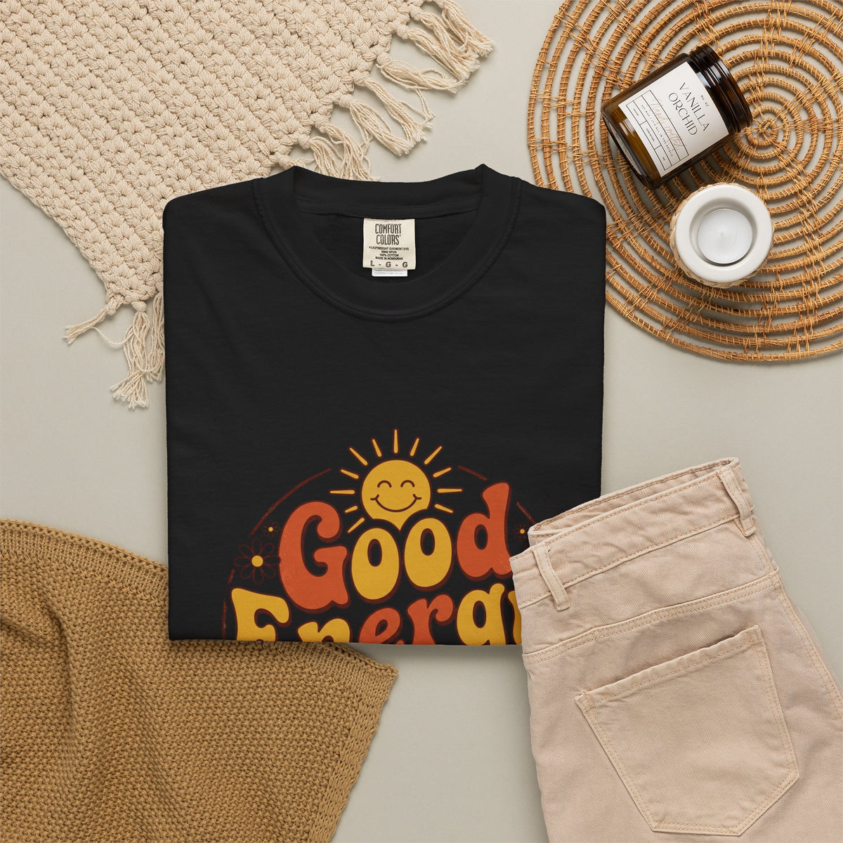 Good Energy Only T-shirt, black, styled flat lay with denim pants and a woven blanket.