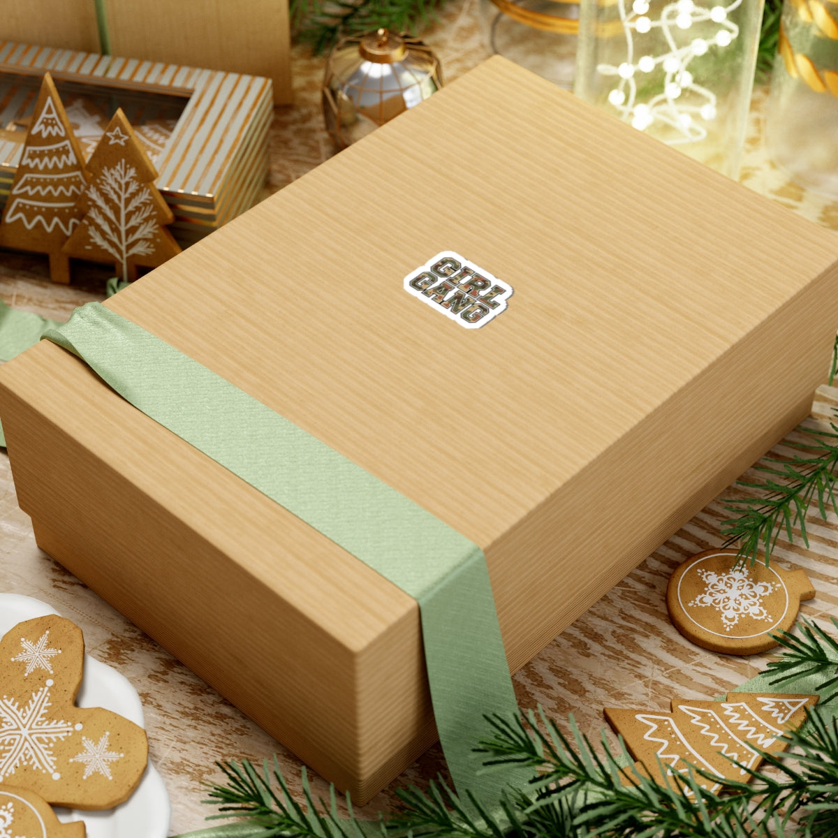 Camo Lettering GIRL GANG Sticker, 2 × 2, applied to a kraft gift box with holiday decor